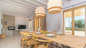 A modern dining area with a wooden table, chairs, and hanging light fixtures. - Can Mosca - Villa With Private Pool. Free Wifi (, Illes Balears)