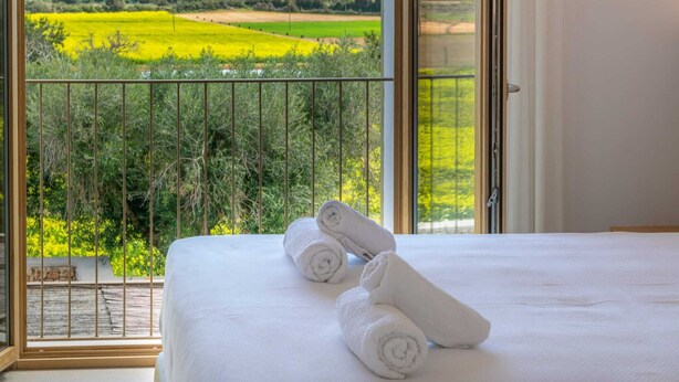 A bedroom with a large window overlooking a green landscape and a balcony with a metal railing. - Can Mosca - Villa With Private Pool. Free Wifi (, Illes Balears)