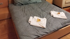 Un llit ben fet amb roba de llit estampada, un panell de fusta al capçal i una butaca beix en una habitació amb parets taronja.