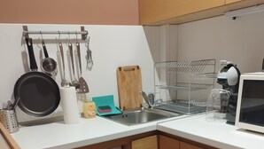 Cuina compacta amb rentadora integrada, un rentapeus i diversos utensilis.