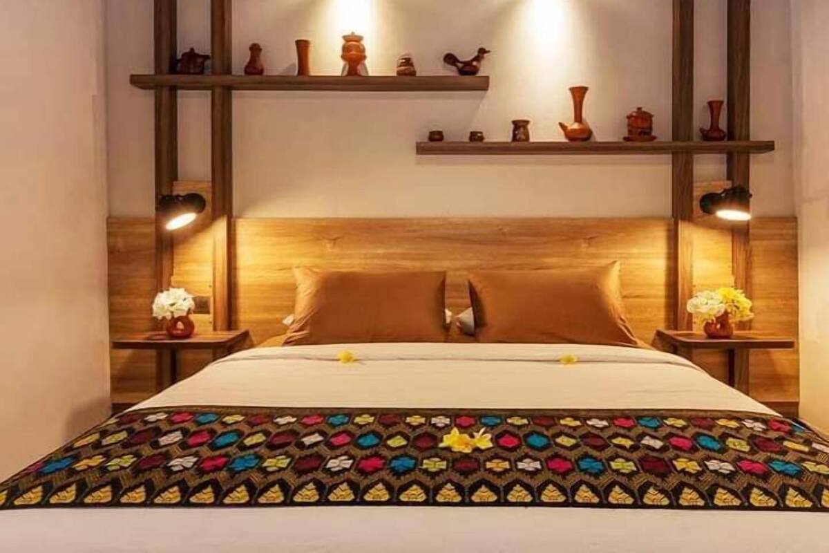 Un lit avec une couvre-lit à motifs, une tête de lit en bois et deux lampes de chevet.