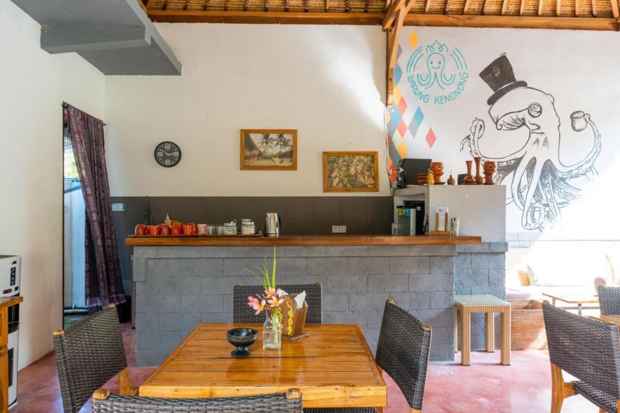 Un restaurante con mesa de madera, sillas de mimbre, mostrador de piedra y un mural de pulpo.
