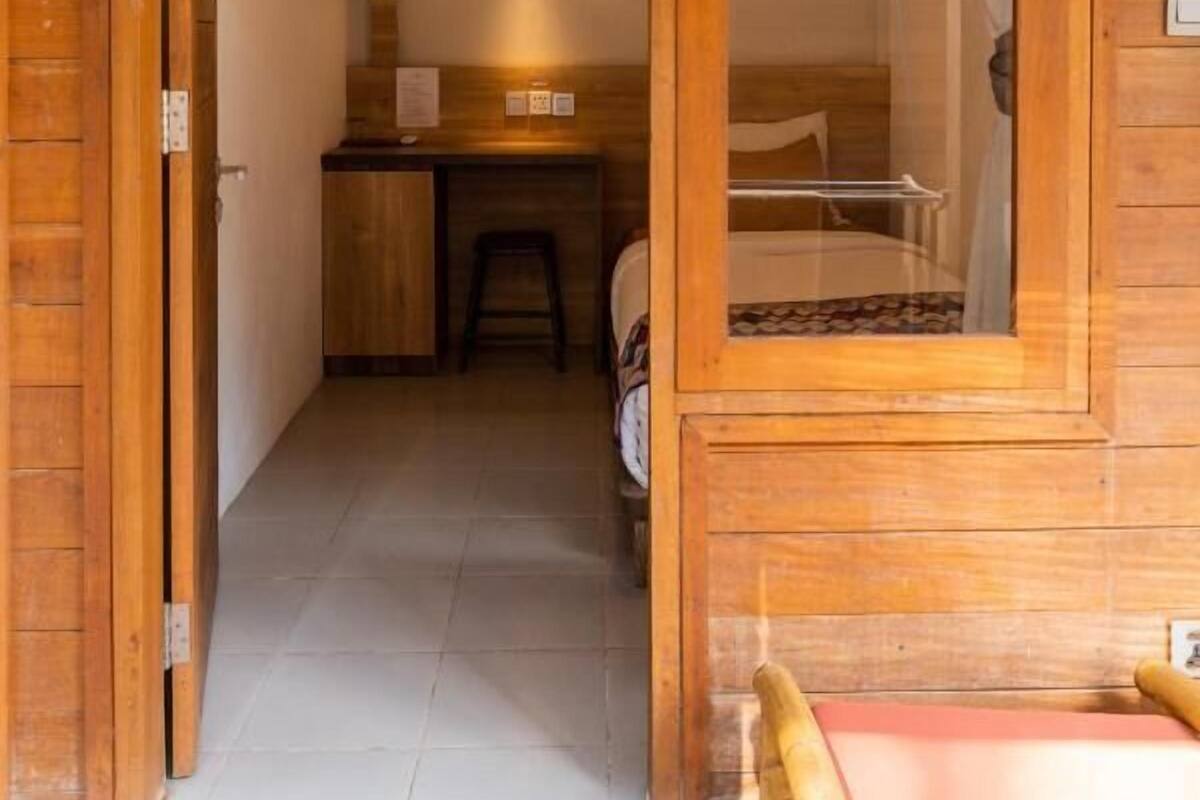 Une pièce en bois comprenant un lit, un bureau et un espace douche.