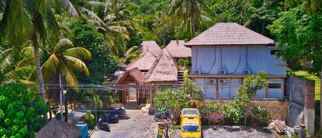 Un complexe hôtelier tropical doté de bungalows aux toits de chaume, d’un parking aménagé et d’une végétation luxuriante.