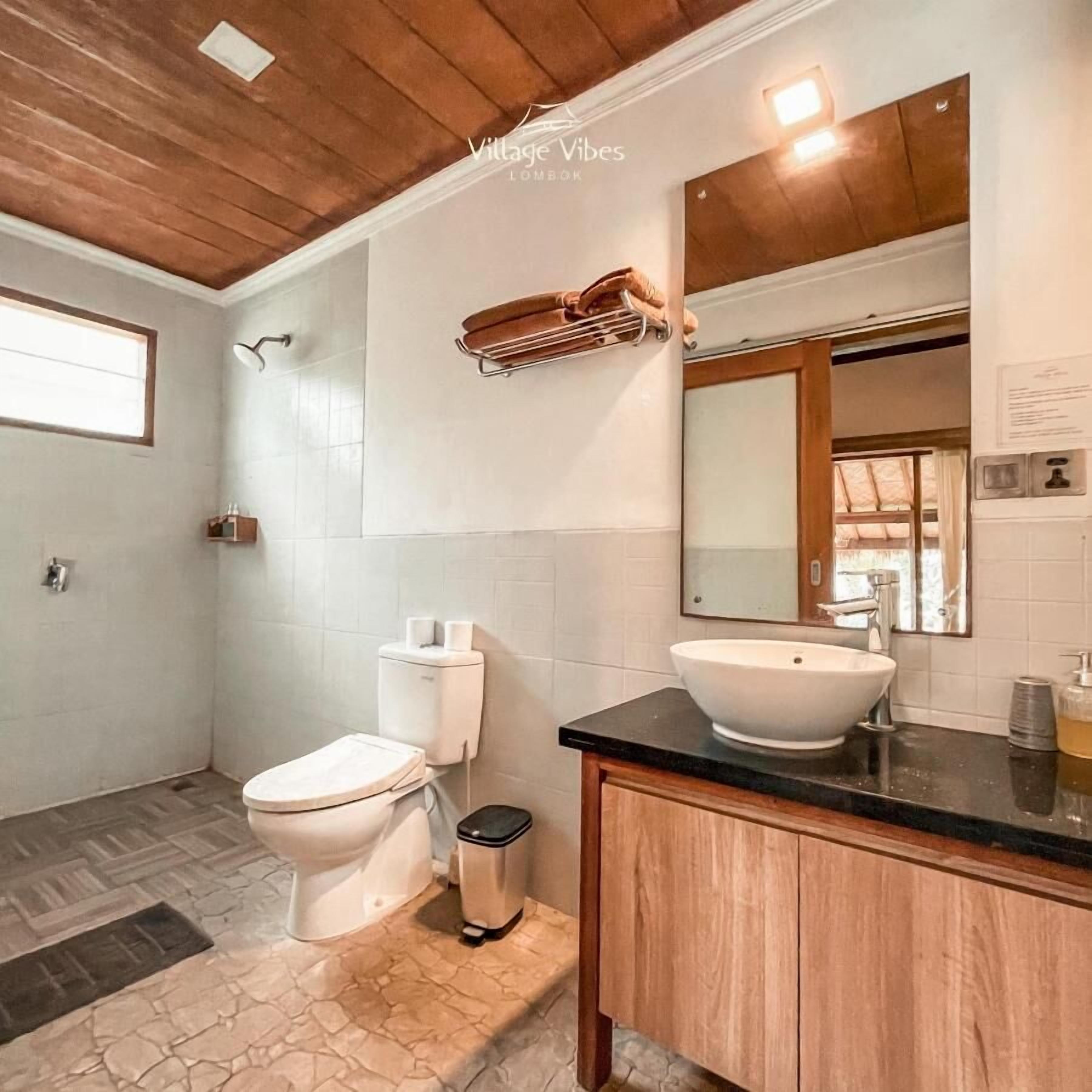 A bathroom with a toilet, bidet, vanity with a sink, and a mirror.