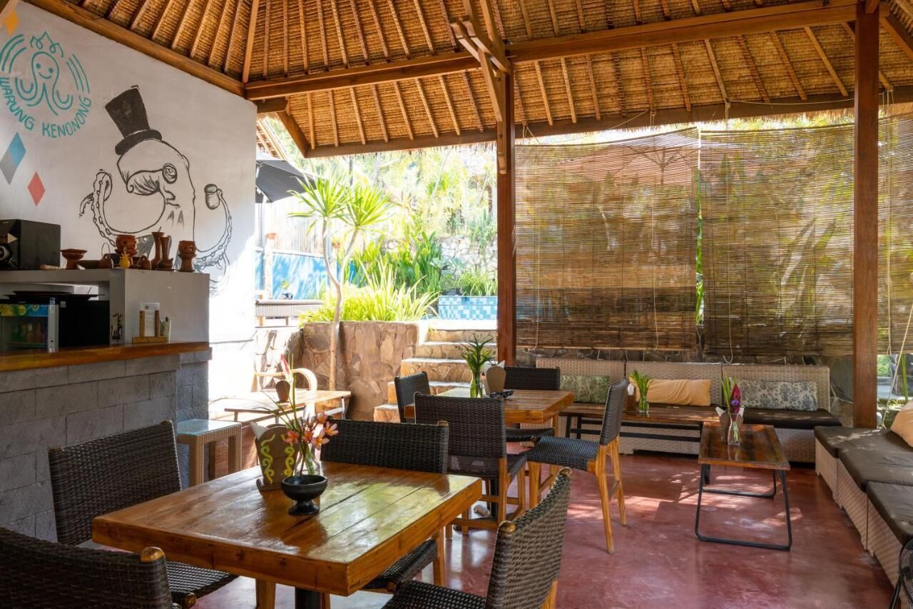 Un espacio exterior para comer con mobiliario de mimbre, una pared de piedra y un mural.