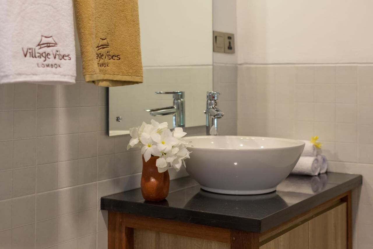A bathroom with a white sink, a mirror, and a towel rack with towels.