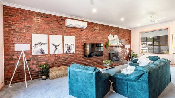 Un salon avec un mur en briques, un téléviseur à écran plat, des canapés de couleur turquoise et une cheminée.