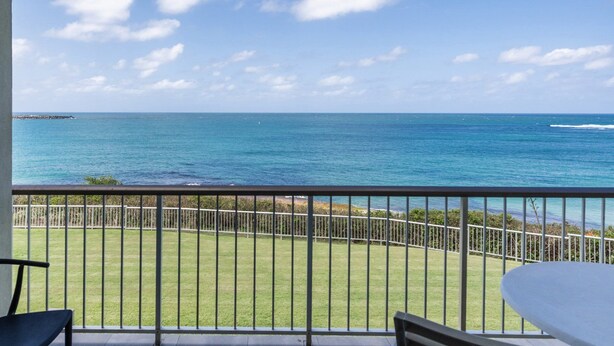 A balcony with a view of the ocean, a grassy area, and a metal railing. - Craigmore On The Beach Unit 11 - Lifestyle Yamba (YAMBA)
