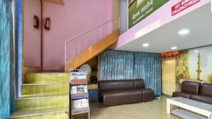 Zona de recepción con una escalera, un mostrador de recepción y un área de descanso con sofás.
