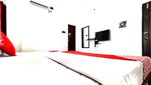 Una habitación con una cama, un armario, un televisor de pared y un aire acondicionado.