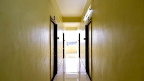 Un pasillo estrecho y bien iluminado con puertas a ambos lados, que conduce a un área luminosa al final.