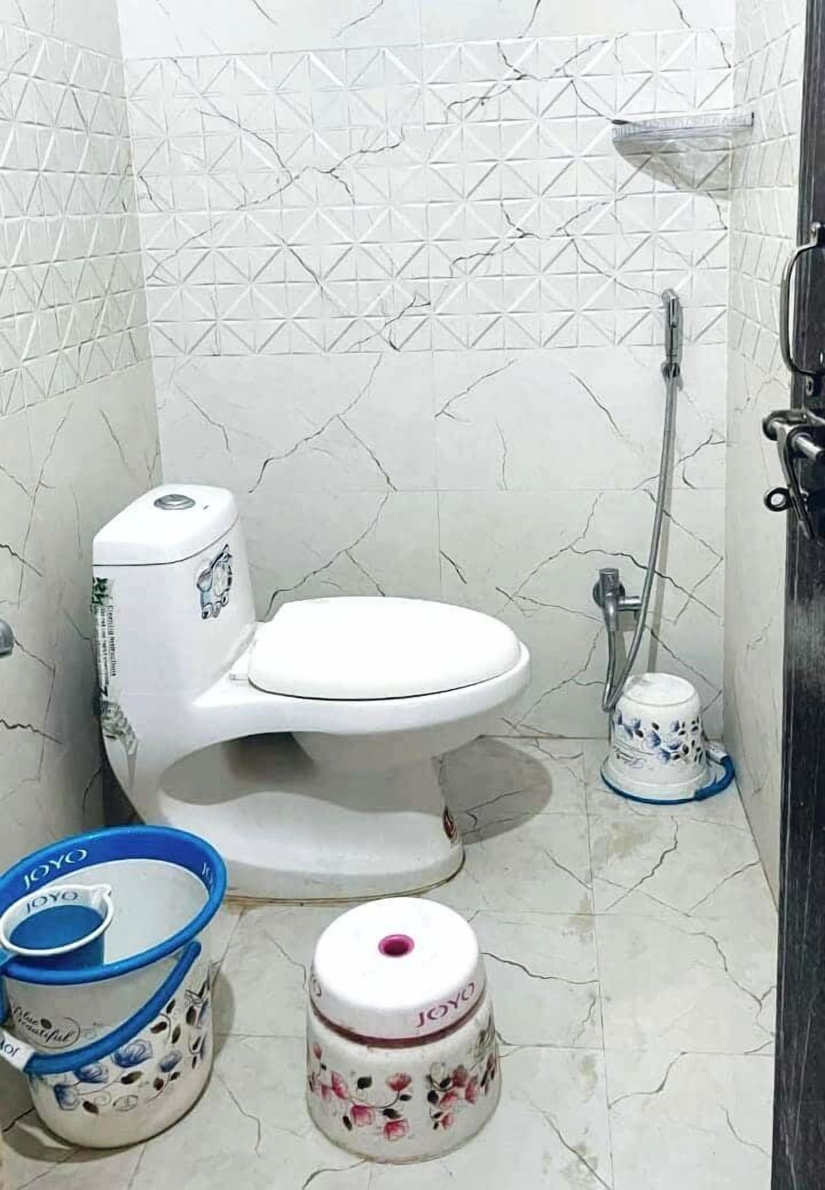 A bathroom with a white toilet, a shower, and two toiletry containers.