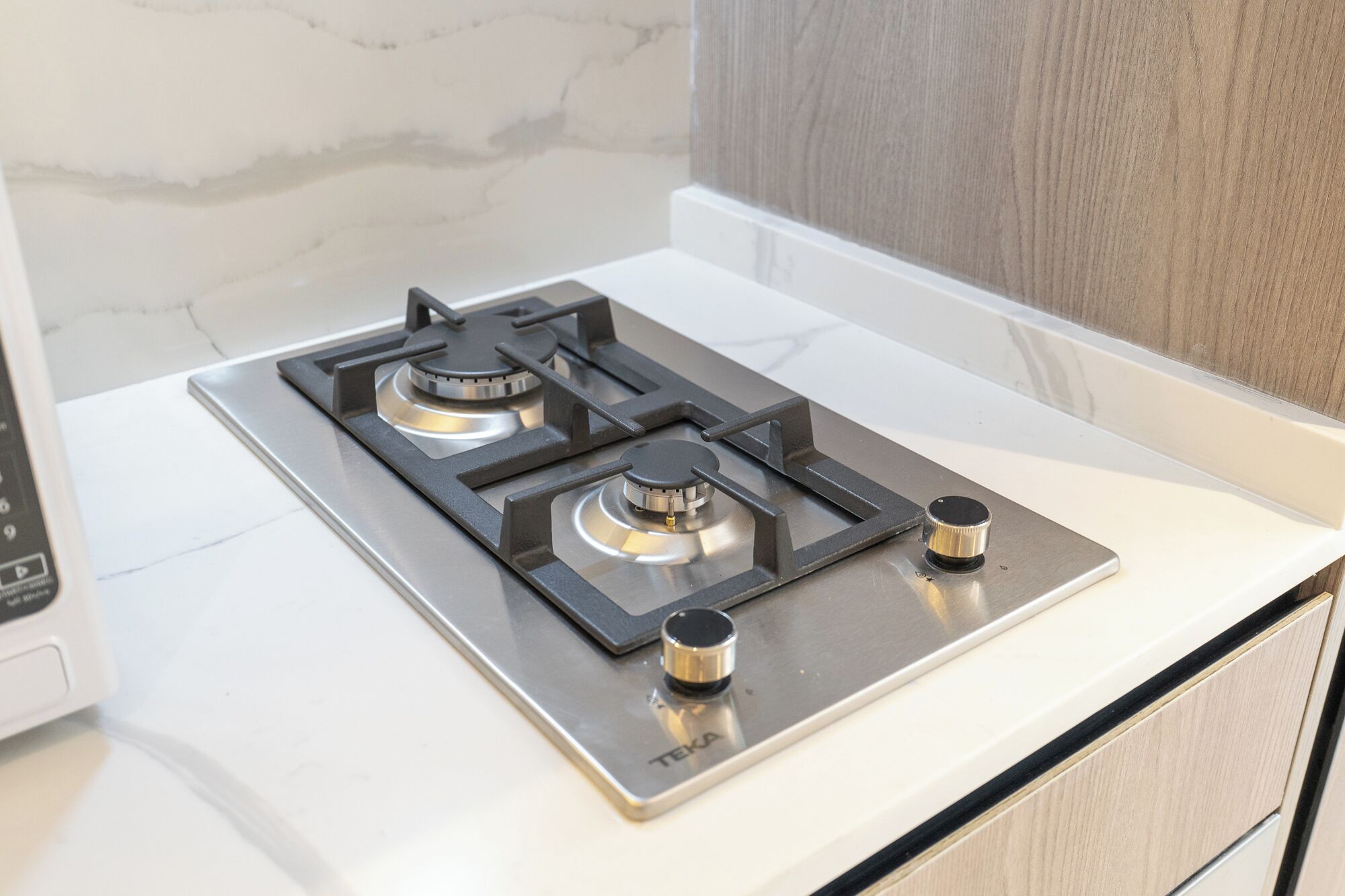 Een keuken met een vierpits gasfornuis, een magnetron en een wit aanrecht.
