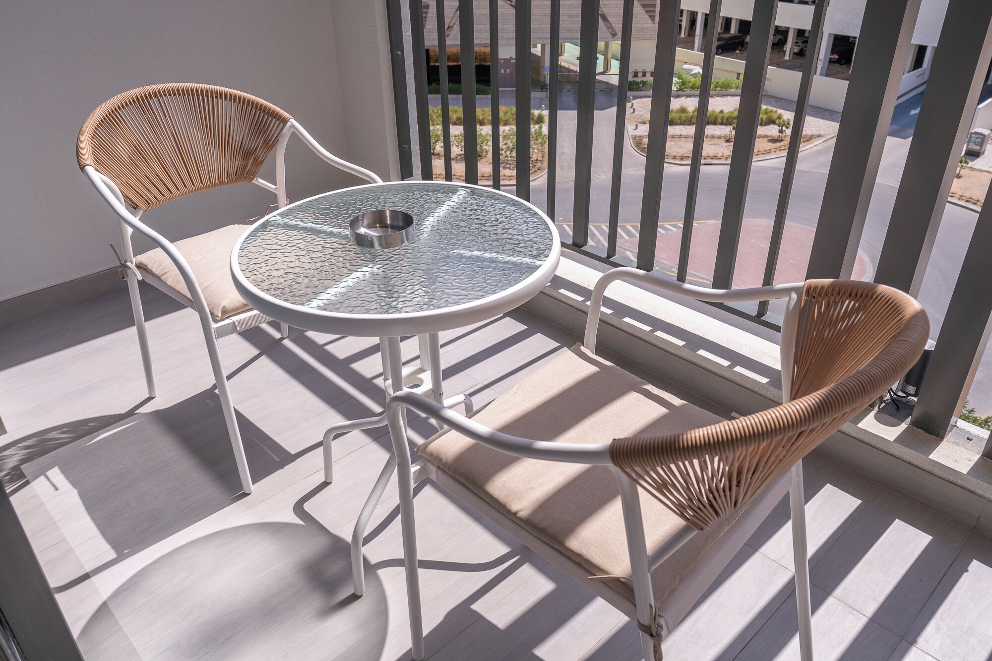 Ein Balkon mit zwei Korbstühlen und einem Glastisch.