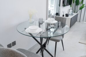 A modern dining area with a glass table, white plates, and clear glassware. - TOP Location | Work and Chill near Miracle Garden (Dubai)