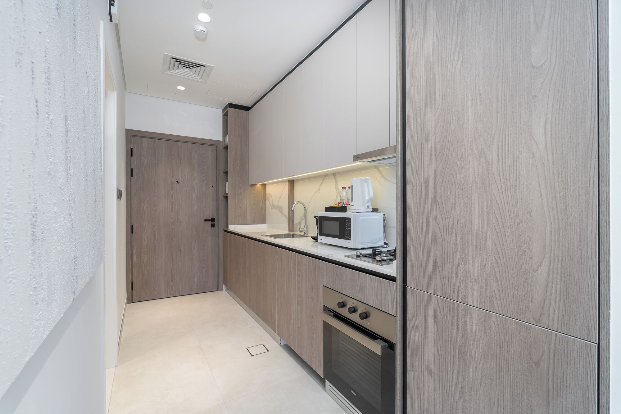 A modern kitchen with wood paneling, a microwave, a coffee maker, and a stove.
