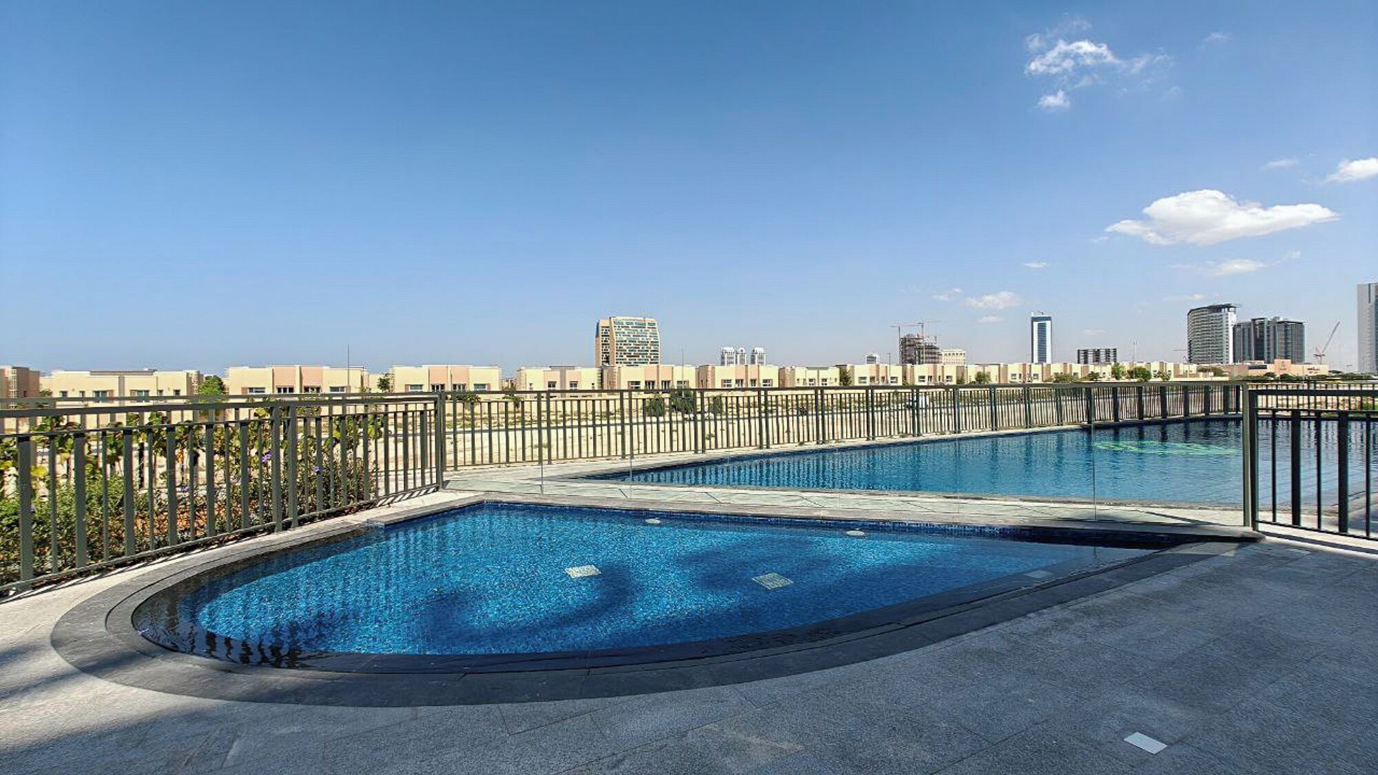 Una piscina en la azotea con un horizonte urbano de fondo.
