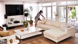 A modern living room with a large flat-screen TV, a sofa, a coffee table, and a potted plant.