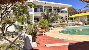 A resort with a pool, outdoor seating, and a white building with multiple balconies.