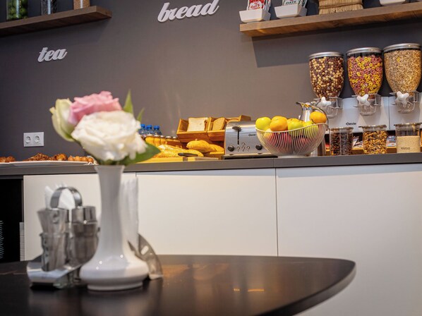 Un buffet de petit-déjeuner proposant divers aliments, une machine à café et un vase rempli de fleurs sur la table.