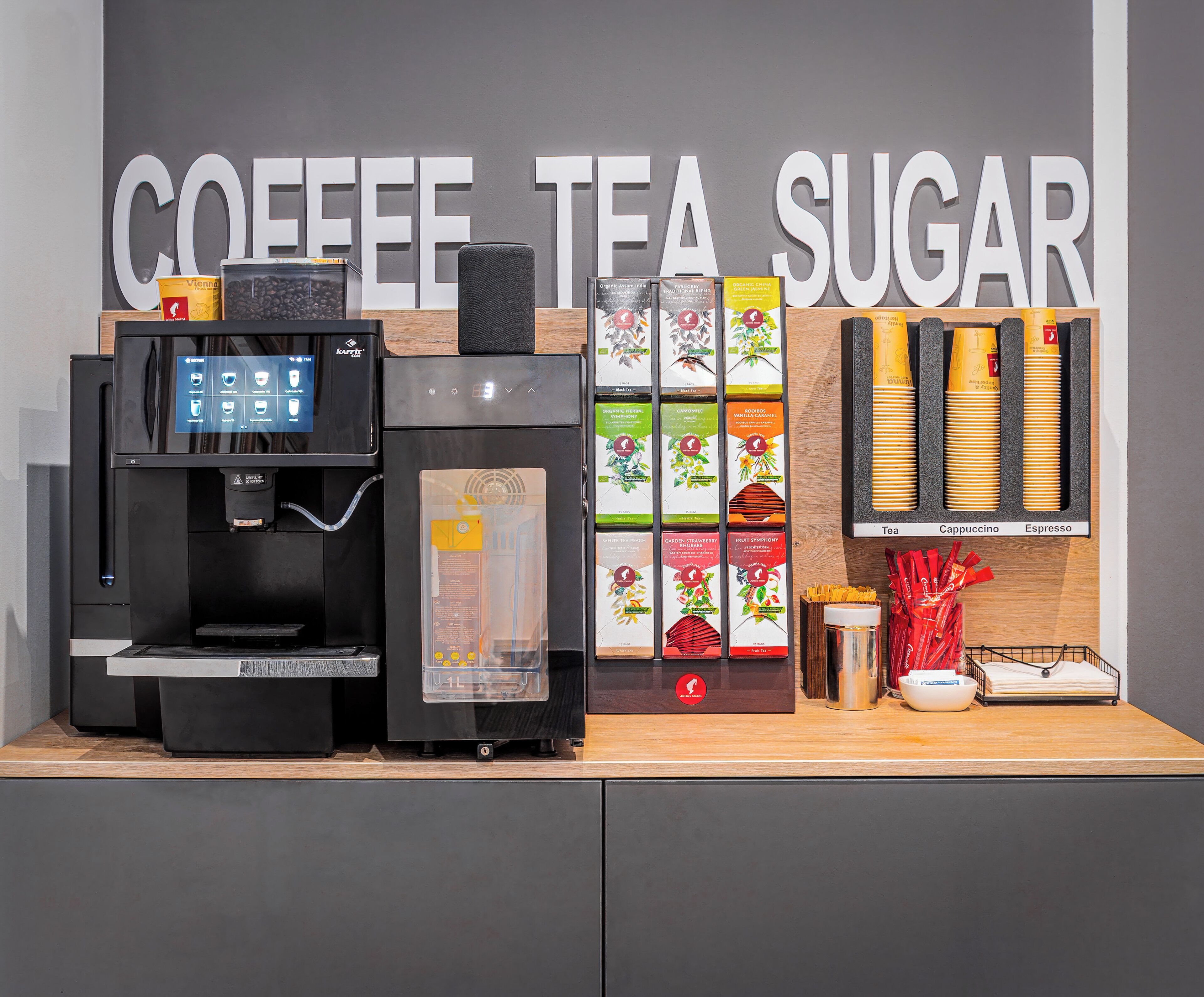 A coffee machine, tea and sugar dispensers, and a display of tea and sugar boxes.