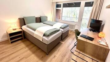 Une chambre à coucher moderne, équipée d’un lit, de tables de chevet, d’un bureau et d’un téléviseur.