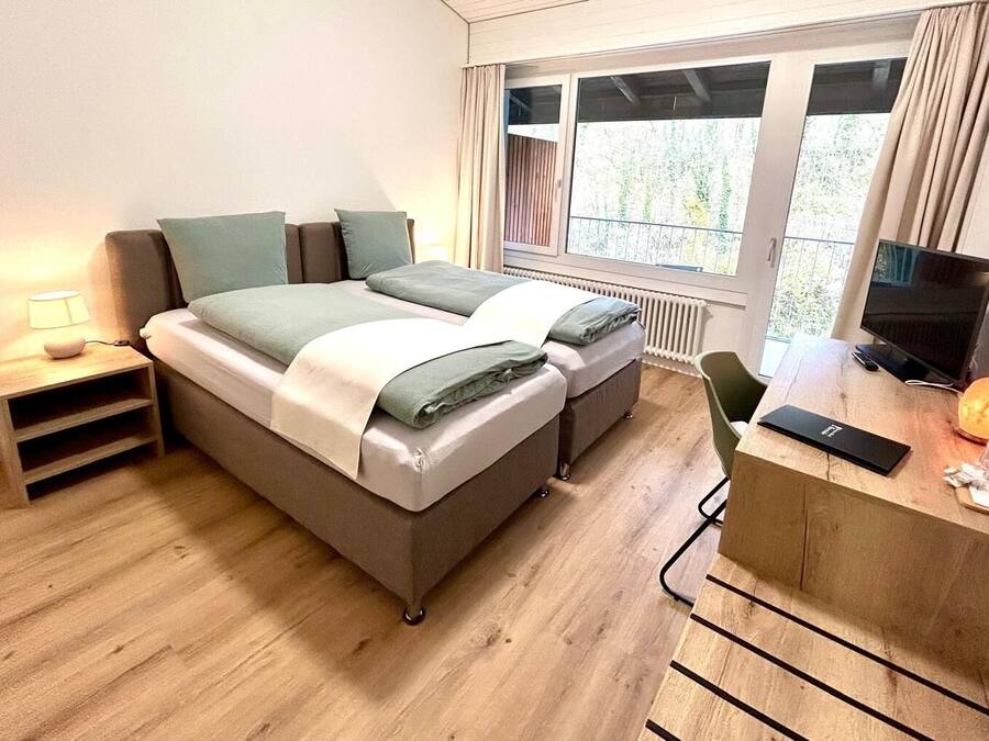 Une chambre à coucher moderne, équipée d’un lit, de tables de chevet, d’un bureau et d’un téléviseur.