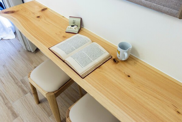 Un escritorio de madera con un libro abierto, una taza y una figurita.