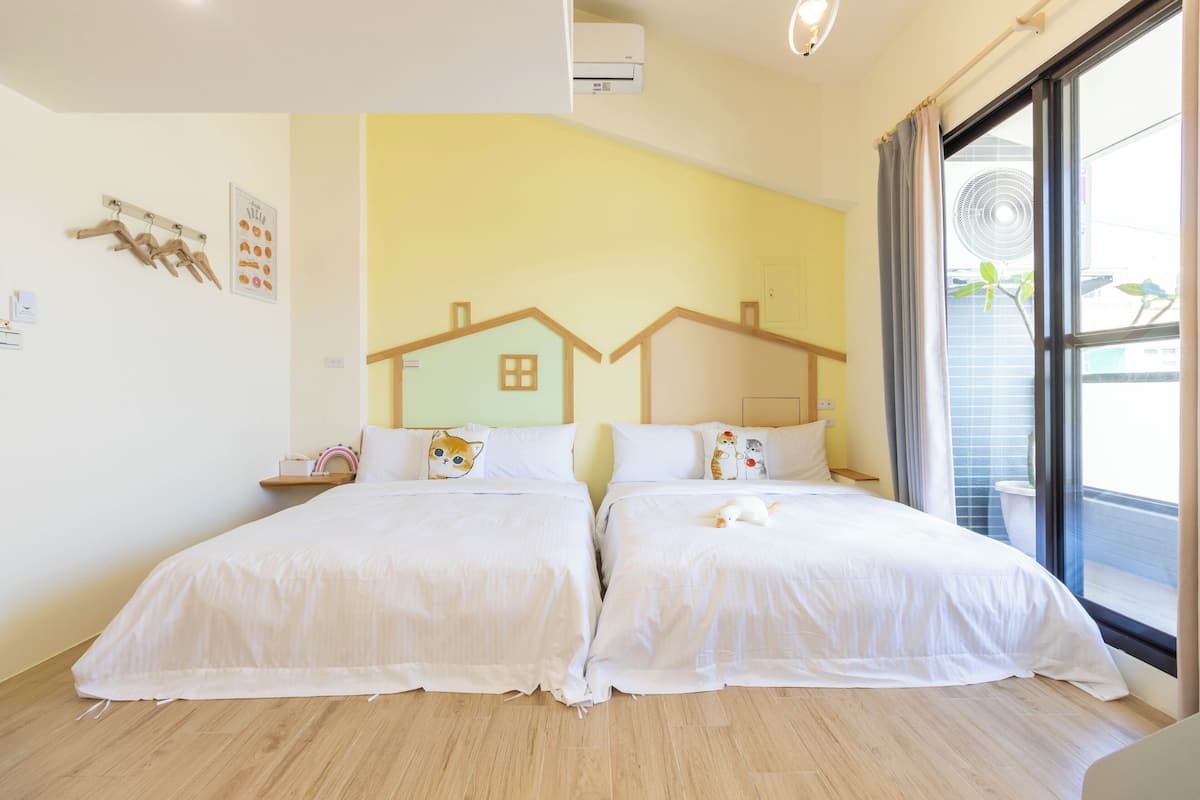 A hotel room with two beds, a large window with a view, and a wall-mounted air conditioner.