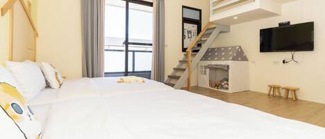 A bedroom with a large bed, a staircase, a TV, and a fireplace.