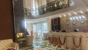 Un hall d’entrée avec un comptoir de réception, un espace salon et un balcon agrémenté de plantes.