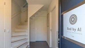 A hallway with a staircase leading to a door labeled "Bed by AI Boutique apartment 16A". - Appartement Bed by Al - Hoofdstraat 16 a Kortgene (Kortgene)