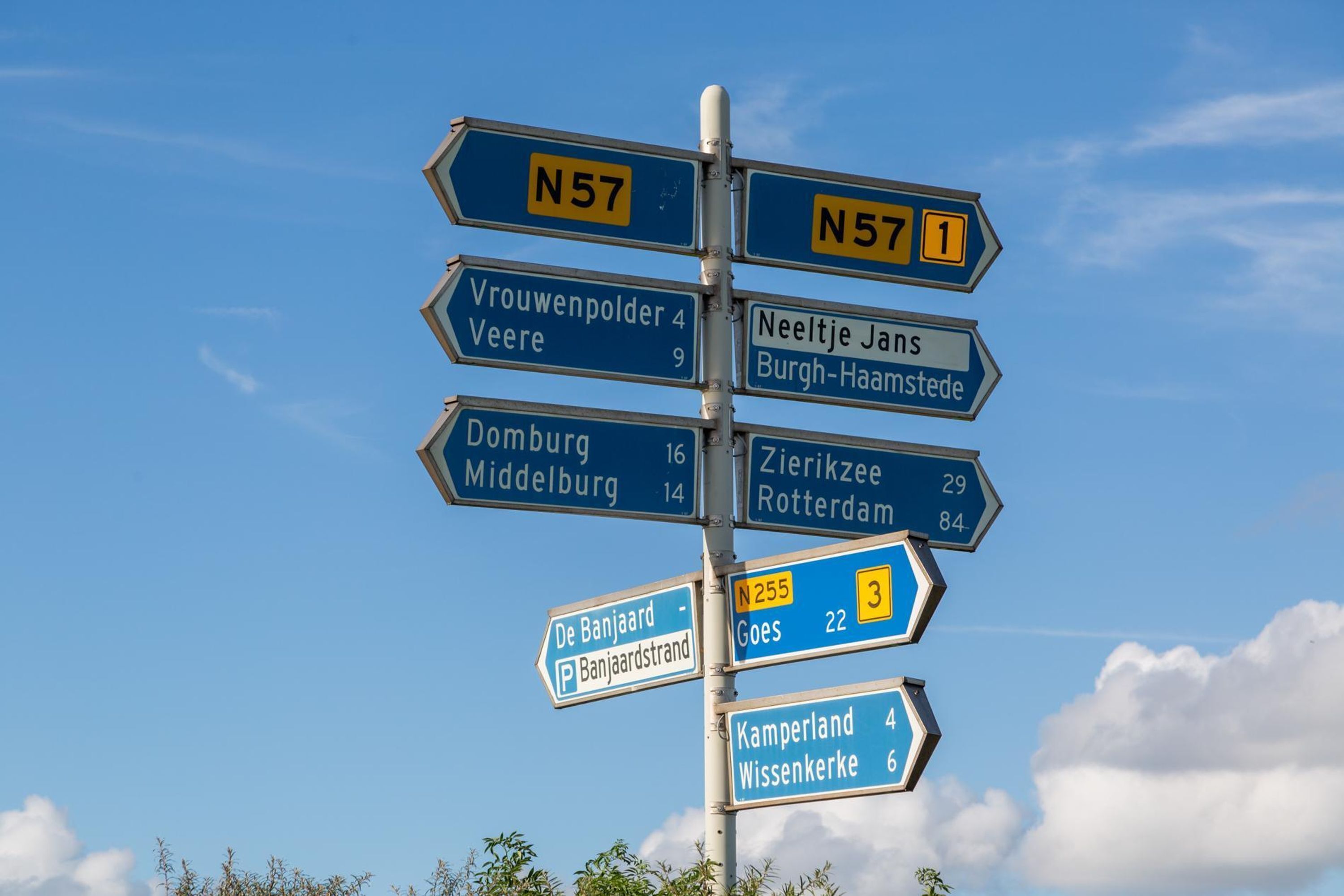 Ein Wegweiser mit mehreren Routennummern und Zielortbezeichnungen.