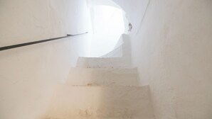 Uma escada estreita com corrimão, conduzindo para cima em direção a uma fonte de luz intensa.