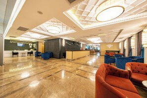 Eine geräumige Lobby mit Marmorboden, einer Rezeption und Sitzbereichen.