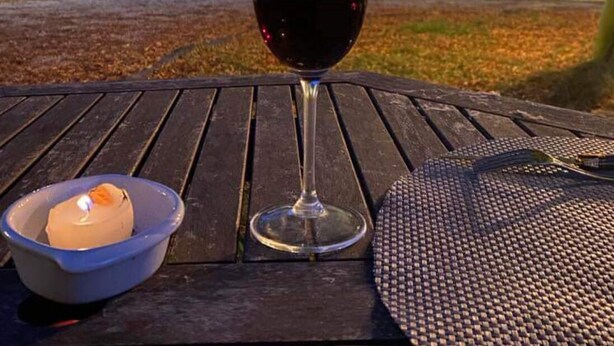 A table with a glass of red wine, a candle, and a bowl of ice cream. - Chamber for young farmers  (Benais)