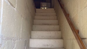 A narrow, concrete stairwell with a wooden handrail and a white door at the top. - Chamber for young farmers  (Benais)