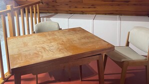 A wooden ceiling with a staircase, a wooden table, and two chairs in a room with a red floor. - Chamber for young farmers  (Benais)
