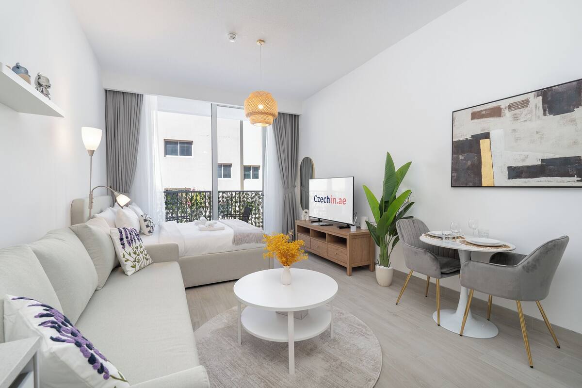 Un salon moderne comprenant un canapé, une table basse ronde, un téléviseur et un coin repas avec des chaises et une table.