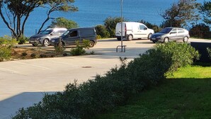 Ein Parkplatz mit mehreren Autos, einer Straßenlaterne und Blick auf das Meer.