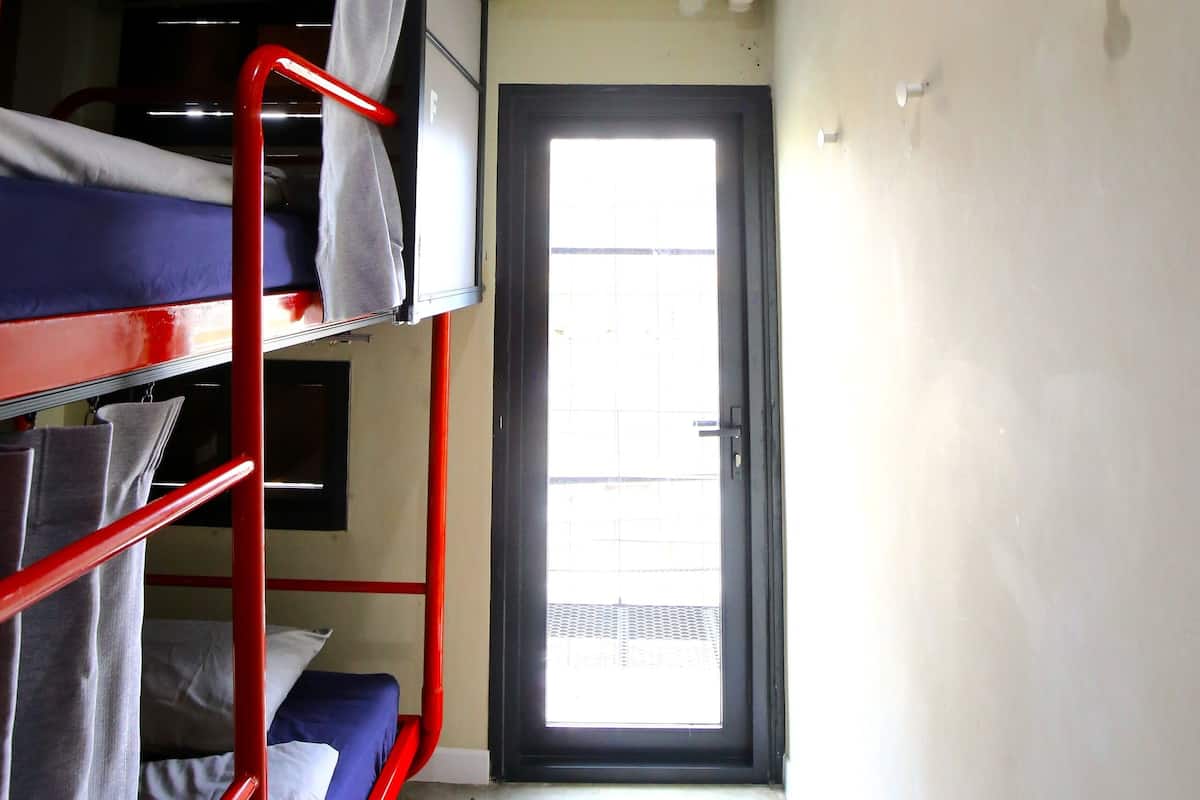 A compact room with bunk beds, a door leading outside, and an air conditioning unit on the wall.