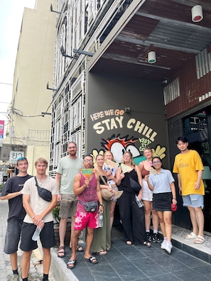 A group of people standing in front of a building with a mural that says "HERE WE GO STAY CHILL". - Here We Go Bangkok (Bangkok)