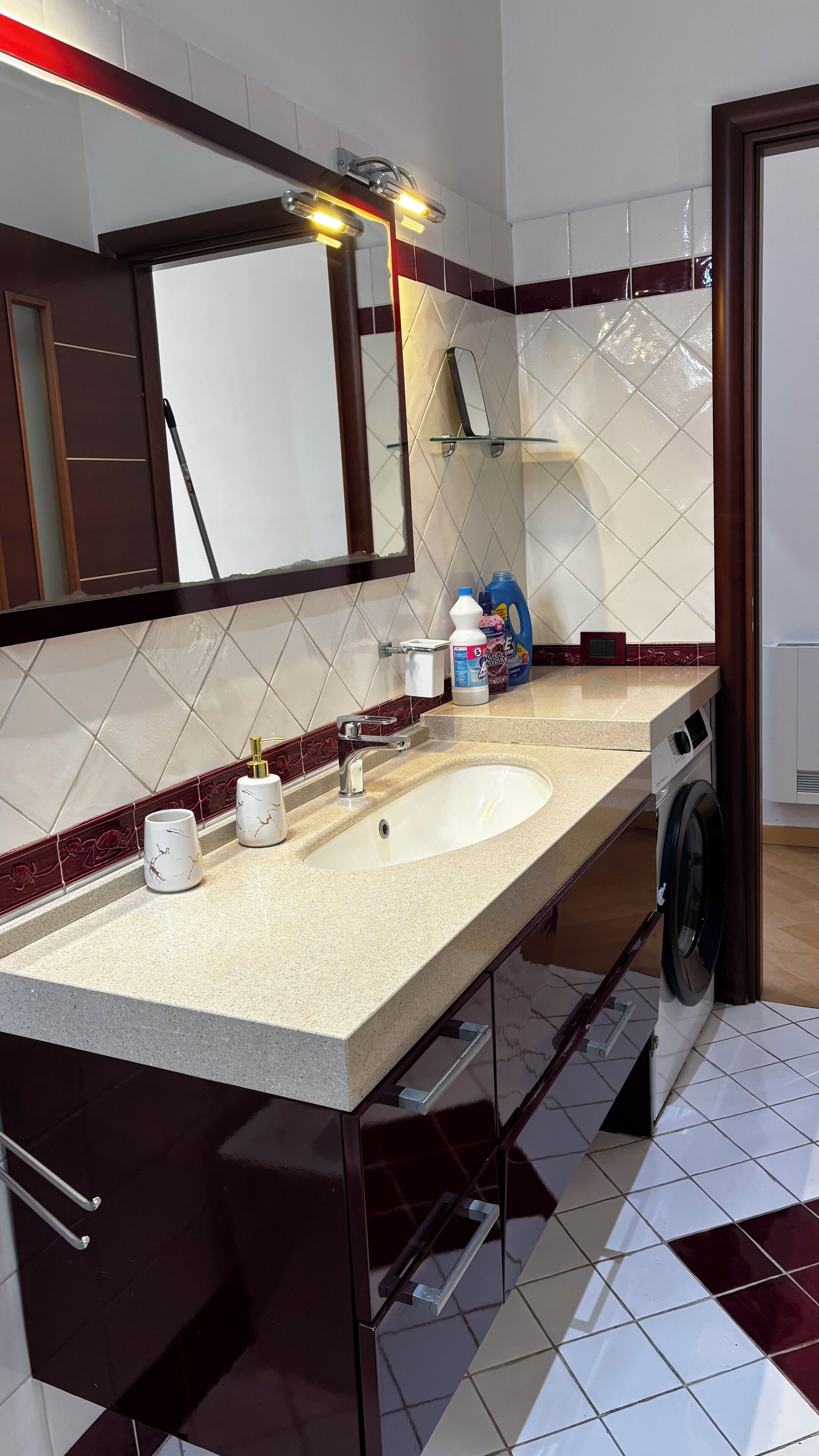 A modern bathroom with a double sink, a mirror, a towel rack, and a washing machine.