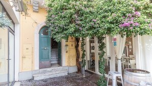 Un patio con un árbol, un barril de madera y una escalera que lleva a una puerta.