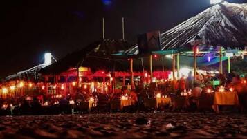 Ein Restaurant direkt am Strand mit Außenplätzen und einem Reetdach.
