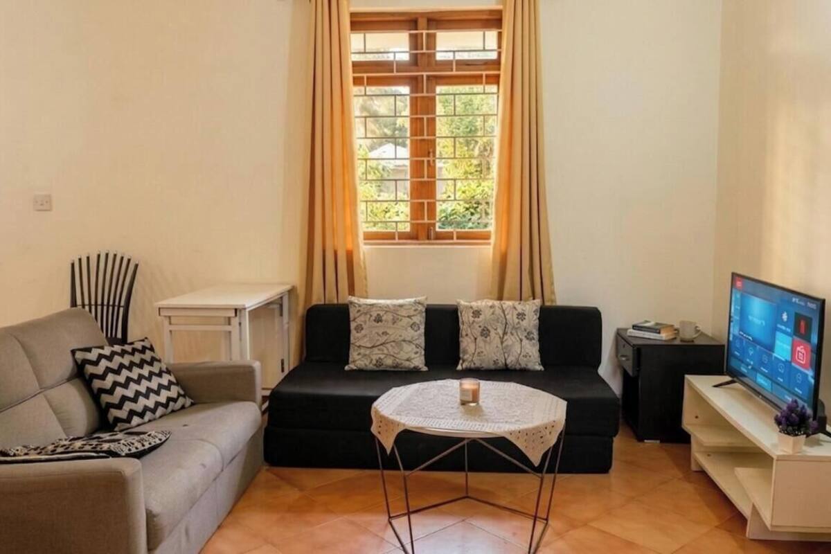 Un soggiorno con divano, un tavolino, televisione e una finestra con tende.