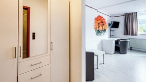 A hotel room with a wardrobe, a desk, a chair, a TV, and a window with curtains. - Comfortable and versatile room -perfect for relaxation, work and exchange (Winterberg)