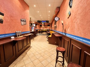 A restaurant interior with a long counter, stools, and a clock on the wall. - Comfortable and versatile room -perfect for relaxation, work and exchange (Winterberg)