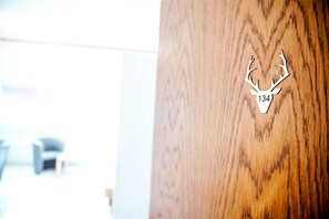 A wooden door with a deer head cutout and the number 134.